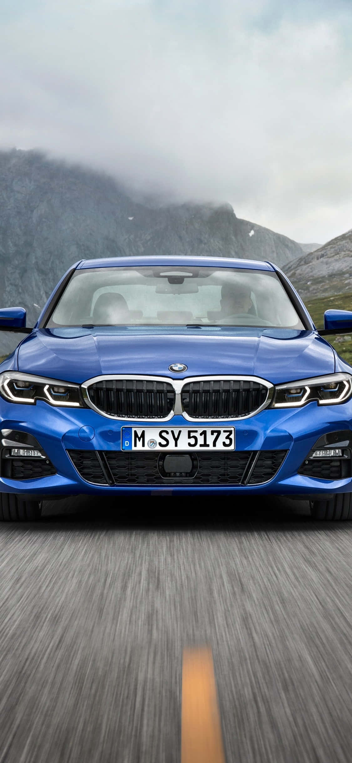 Ένα λευκό BMW X Series παρκαρισμένο δίπλα σε ένα iPhone X Ταπετσαρία