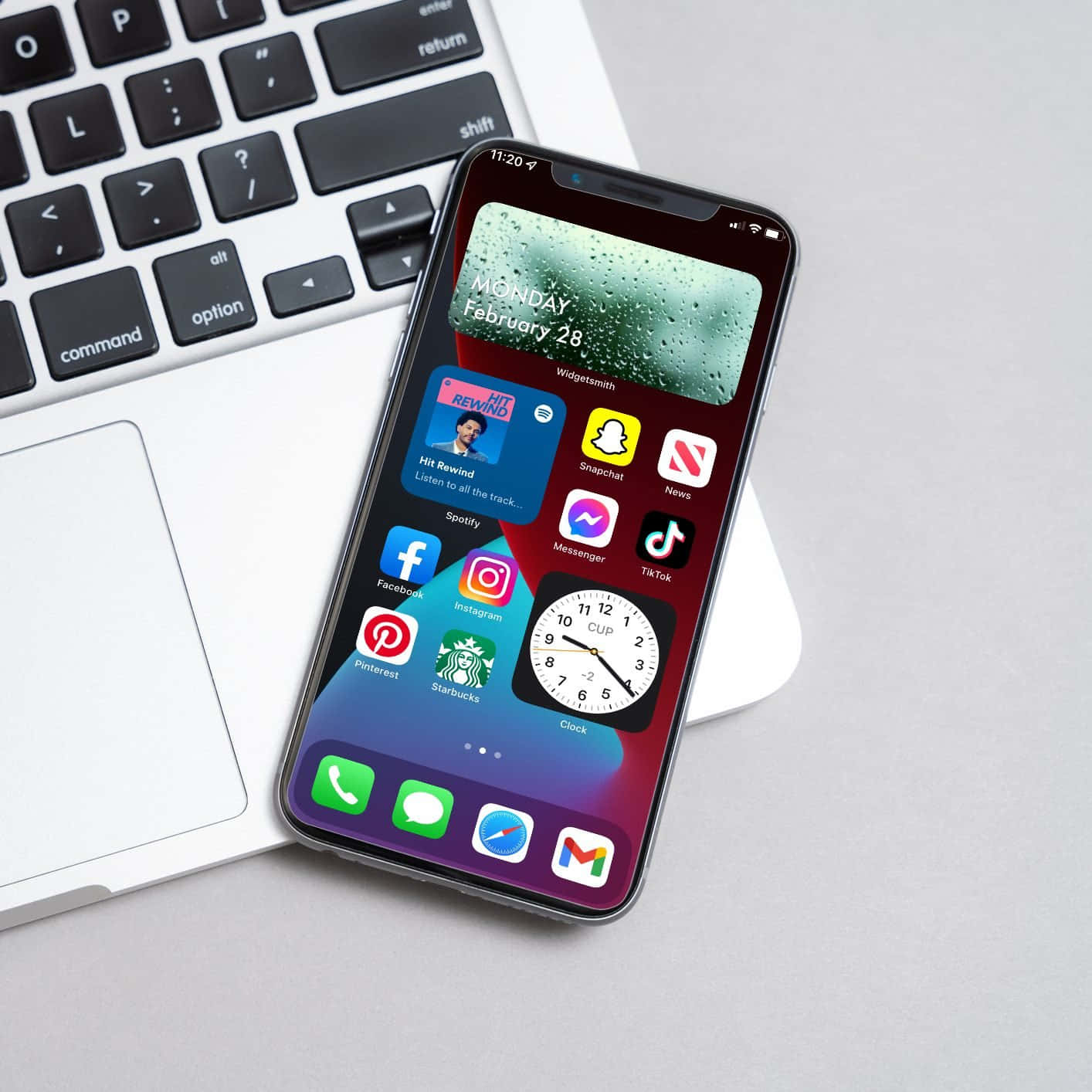 ένα iPhone xr με εφαρμογές πάνω του δίπλα σε ένα laptop Ταπετσαρία
