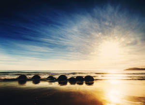Ταπετσαρία ανατολής ηλίου στην παραλία Moeraki Boulders