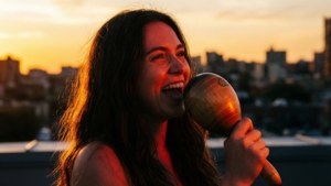 Ο Vivo ερμηνεύει ένα μελωδικό τραγούδι σε μια ταράτσα καθώς δύει ο ήλιος, κρατώντας μαράκες.