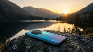 Κινητό Huawei πάνω σε έναν βράχο με θέα σε μια ορεινή λίμνη στο ηλιοβασίλεμα, γαλήνιο τοπίο.