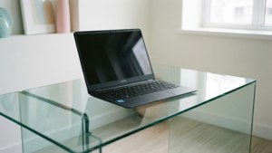Μια καθαρή μινιμαλιστική σκηνή με ένα Chromebook σε γυάλινο τραπέζι.